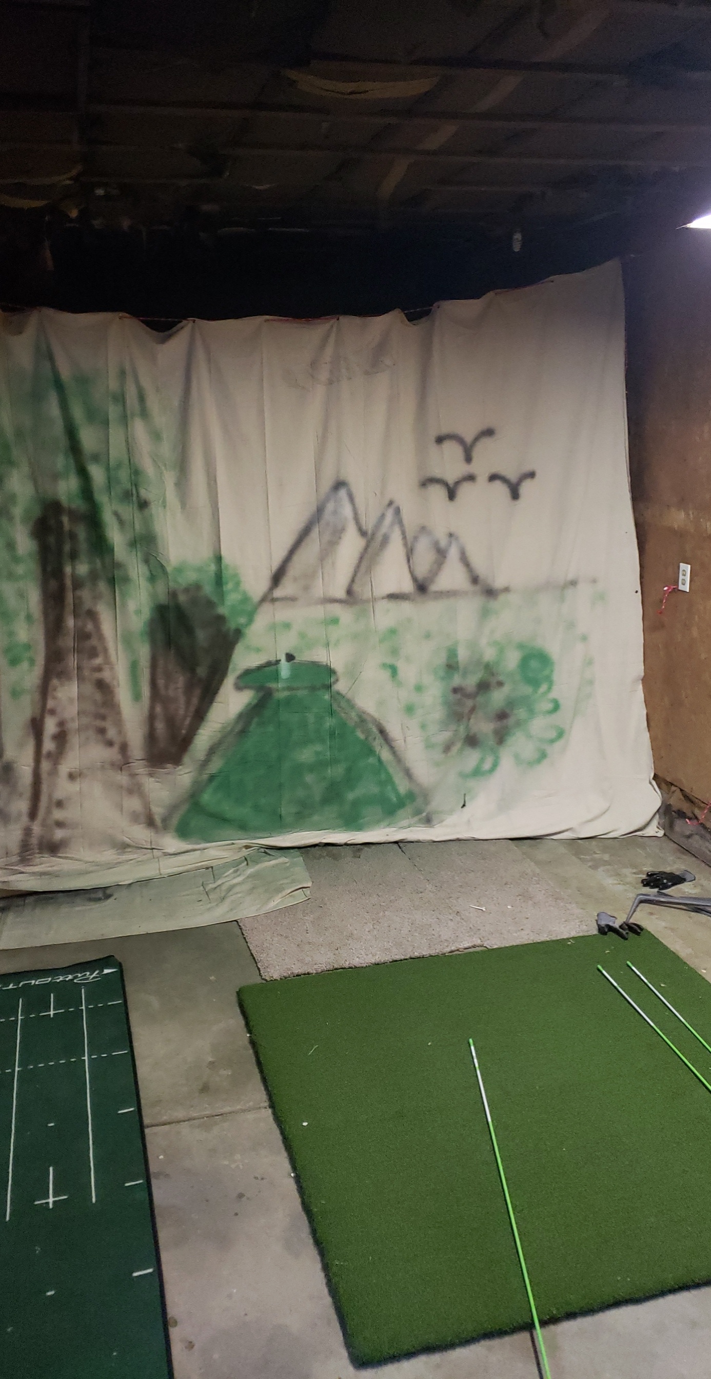 First budget golf simulator build with impact net, mat, and a spray-painted canvas backdrop